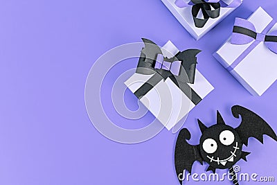 Halloween paper gift boxes with black bows and silly felt bat on side of purple background with copy space Stock Photo