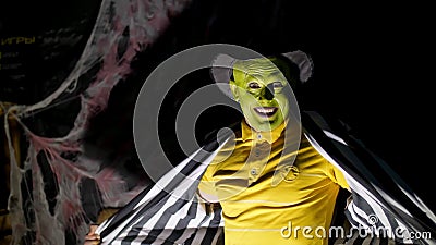 Halloween party, night, twilight, in the rays of light, a man with a terrible make-up, with a green face and a hat Stock Photo