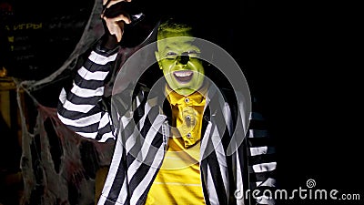 Halloween party, night, twilight, in the rays of light, a man with a terrible make-up, with a green face lifts his hat Stock Photo