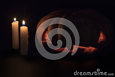 Halloween pumpkin and candle on dark background. Halloween eve banner template. Carved pumpkin with creepy face. Stock Photo