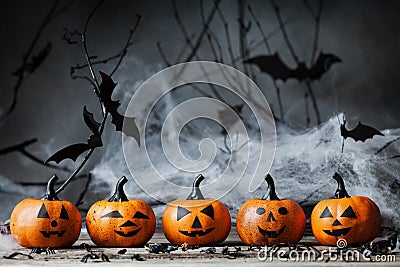 Halloween pumpkin heads with funny smile and spooky decoration on dark wood. Stock Photo