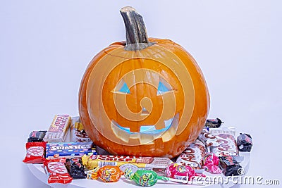 A halloween pumpkin jack-o-lantern with popular halloween candies brands on a white Editorial Stock Photo