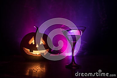 Halloween pumpkin orange cocktails. Festive drink. Halloween party. Funny Pumpkin with a glowing cocktail glass on a dark toned fo Stock Photo