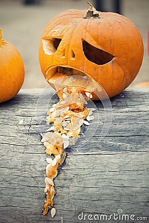 Halloween pumpkin vomit throw up on the tree trunk Stock Photo