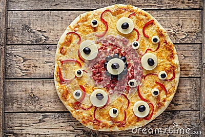 Halloween scary food monster pizza with eyes on vintage wooden table Stock Photo