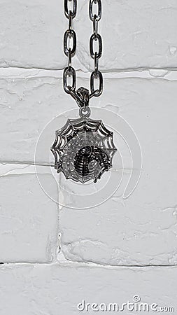 Halloween themed hanging spider hanging on a chain on a white stone wall Stock Photo