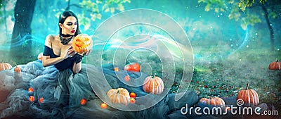Halloween witch with a carved pumpkin and magic lights in a forest Stock Photo