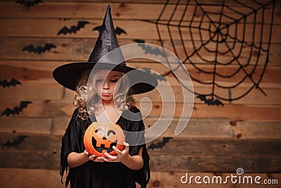 Halloween Witch concept - little caucasian witch child disappointing with no candy in halloween candy pumpkin jar. over bat and sp Stock Photo