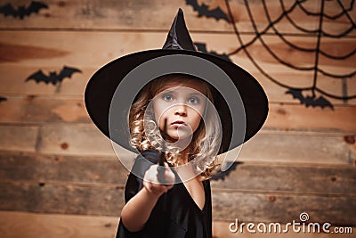 Halloween Witch concept - little witch child enjoy playing with magic wand. over bat and spider web background. Stock Photo