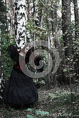 Halloween Witch in a dark forest. Beautiful young woman in witches costume . Halloween art design. Horror Background For Halloween Stock Photo