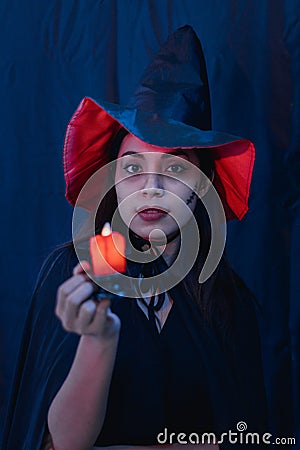 Halloween witch woman portrait holding candle, fashion young woman going to party with spooky costume, makeup scary faces, having Stock Photo