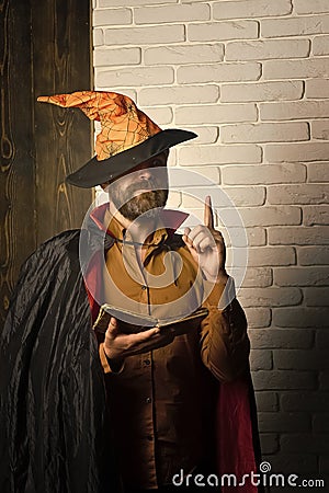 Halloween wizard reading book on brick wall Stock Photo