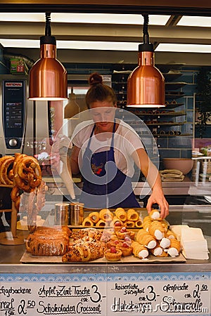 Hallstatt, Austria, September 2019. A girl in a black apron sells traditional Austrian pastries. Delicious crispy cream cake Editorial Stock Photo
