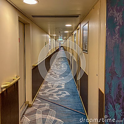 A hallway on a cruise ship with blue geometric patterned carpet and cream colored walls Editorial Stock Photo