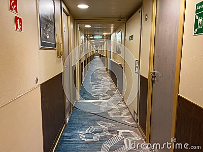 A hallway on a cruise ship with blue geometric patterned carpet and cream colored walls Editorial Stock Photo