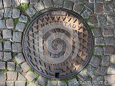 Halmstad, Sweden - August 21, 2022: Halmstad city manhole cover on street with cobblestone pavement, top view Editorial Stock Photo