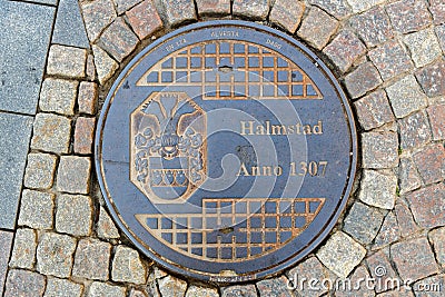 Halmstad city manhole cover on street with cobblestone pavement, top view Editorial Stock Photo