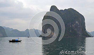 Halong Bay - Vietnam - Large Karsts and small traditional fishing boat Stock Photo