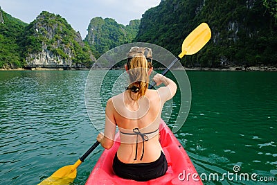 Halong Bay / Vietnam, 06/11/2017: Woman on kayak paddling through karst islands and dense jungle in Halong Bay / Cat Ba island Stock Photo