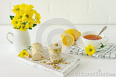 Halva with pistachio served on white wooden desk with flowers and tea Stock Photo