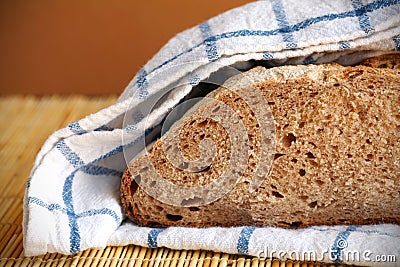 Halved rye bread loaf wrapped in the kitchen towel Stock Photo