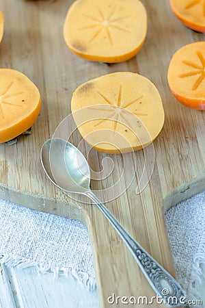 Halves of persimmon fruit on brown wooden background. Stock Photo