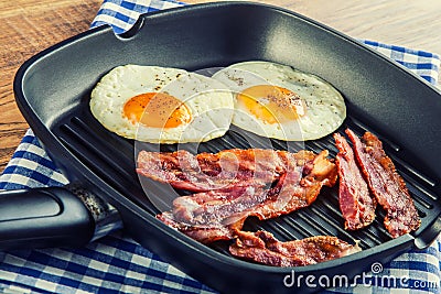 Ham and Egg. Bacon and Egg. Salted egg and sprinkled with black pepper. Grilled bacon, two eggs in a Teflon pan Stock Photo