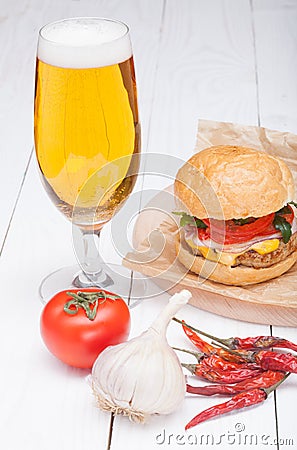 Hamburger cheese onions sauce tomatoes on paper and beer Stock Photo