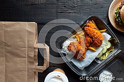 Hamburger, french fries and fried chicken in takeaway containers on the wooden background. Food delivery and fast food concept Stock Photo