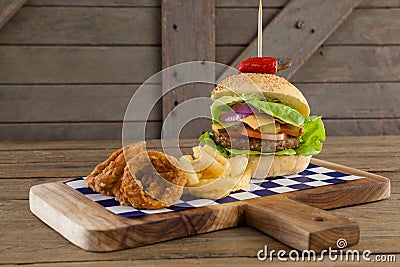 Hamburger, onion ring and french fries on chopping board Stock Photo