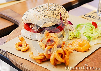 Hamburger with tuna fish, salad and fried calamary in restaurant of Syracuse, Sicily Stock Photo