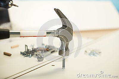 Hammer cuts a cruciform bolt and nail into a furniture closet during assembly of purchased furniture Stock Photo