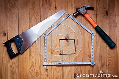 Hammer, hand saw, meter, nails are in form of house. House concept. Stock Photo