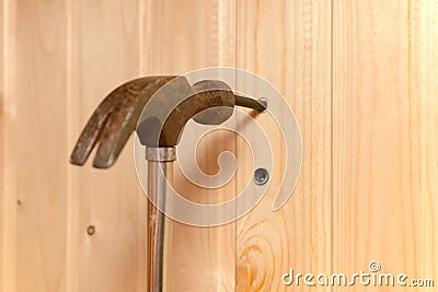 hammer hits the dowel and hammers it into a hole in the wooden wall Stock Photo