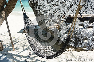 Hammock hanging with tree in shade at seaside sandy beach Stock Photo