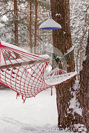 Hammock under the snow in the garden in winter. Summer and vacation memories Stock Photo