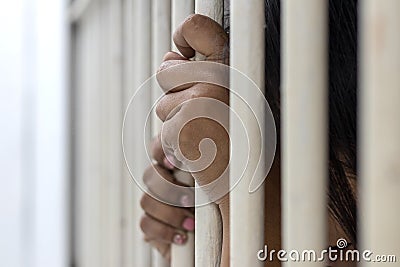 The hand of the accused woman caught the bars of the prison room Stock Photo