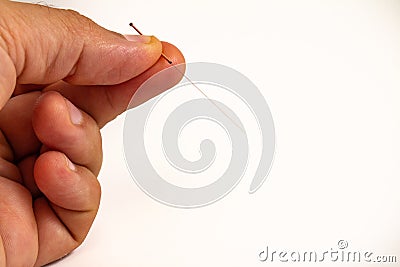 Hand of an acupuncturist holding a long thin acupuncture needle. Man`s hand and metal needle Stock Photo