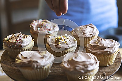 Hand adding sprinkles to chocolate cupcake food photography recipe idea Stock Photo