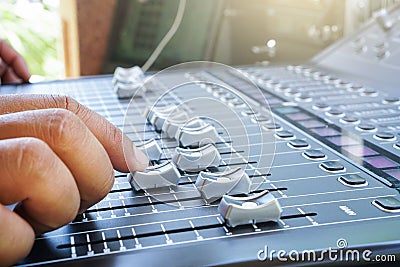 Hand adjusting audio mixer console buttons, faders and sliders. Stock Photo