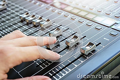 Hand adjusting audio mixer console buttons, faders and sliders. Stock Photo
