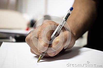 Hand with amputated index finger writing with a pen in a white paper Stock Photo