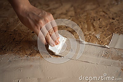 Hand applies the putty with a spatula Stock Photo