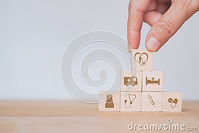 hand arrange health and medical icon on wooden cube blocks, heart and elderly on top, for health insurance, wellness, Stock Photo