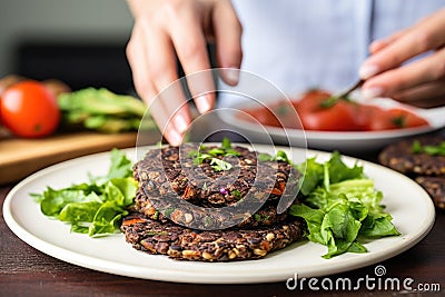 hand arranging black bean burgers on a plate Stock Photo