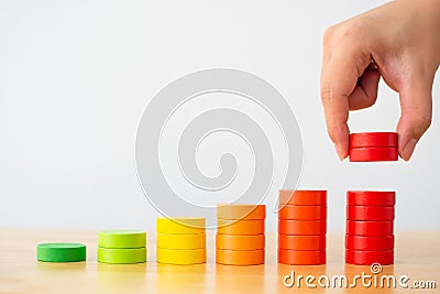 Hand arranging wood block multicolor stacking step as staircase on wooden table Stock Photo