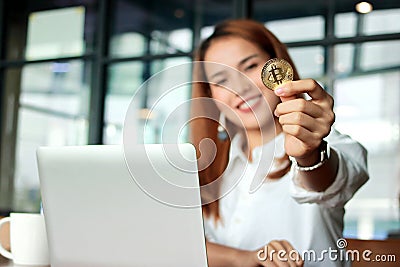 Hand of Asian business woman showing cryptocurrency golden bitcoin coin in office. Virtual money on digital. Stock Photo