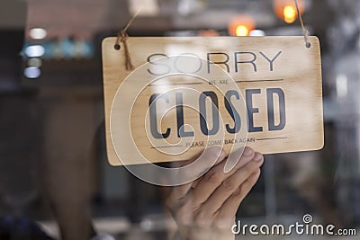 Hand of asian owner retail ,coffee shop woman turning sign board to closed. Protection to pandemic of coronavirus. Close store, Stock Photo
