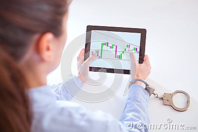 Hand attached with handcuffs and tablet with a financial graph on the screen Stock Photo