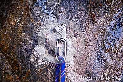 Hand attaching carabiner on rock with blue rope Stock Photo